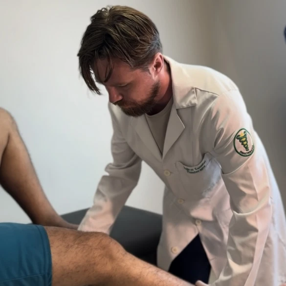 Andrei Cuzuioc examinando a região do joelho durante um atendimento.