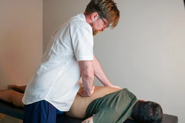 Andrei Cuzuioc realizando terapia manual na região das costas durante um atendimento.